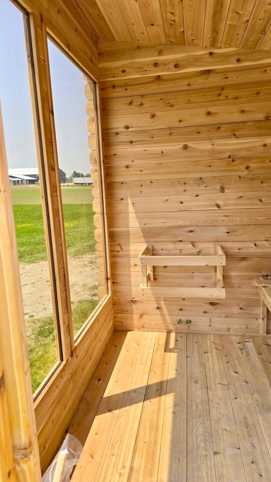 Wooden sauna interior with large windows overlooking a field