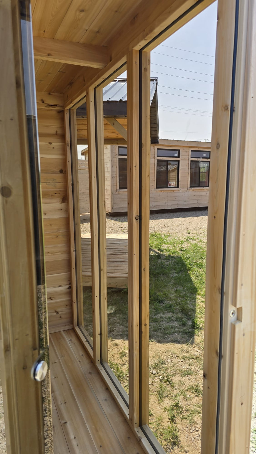 Wooden interior of a sauna with large windows showing an exterior view.