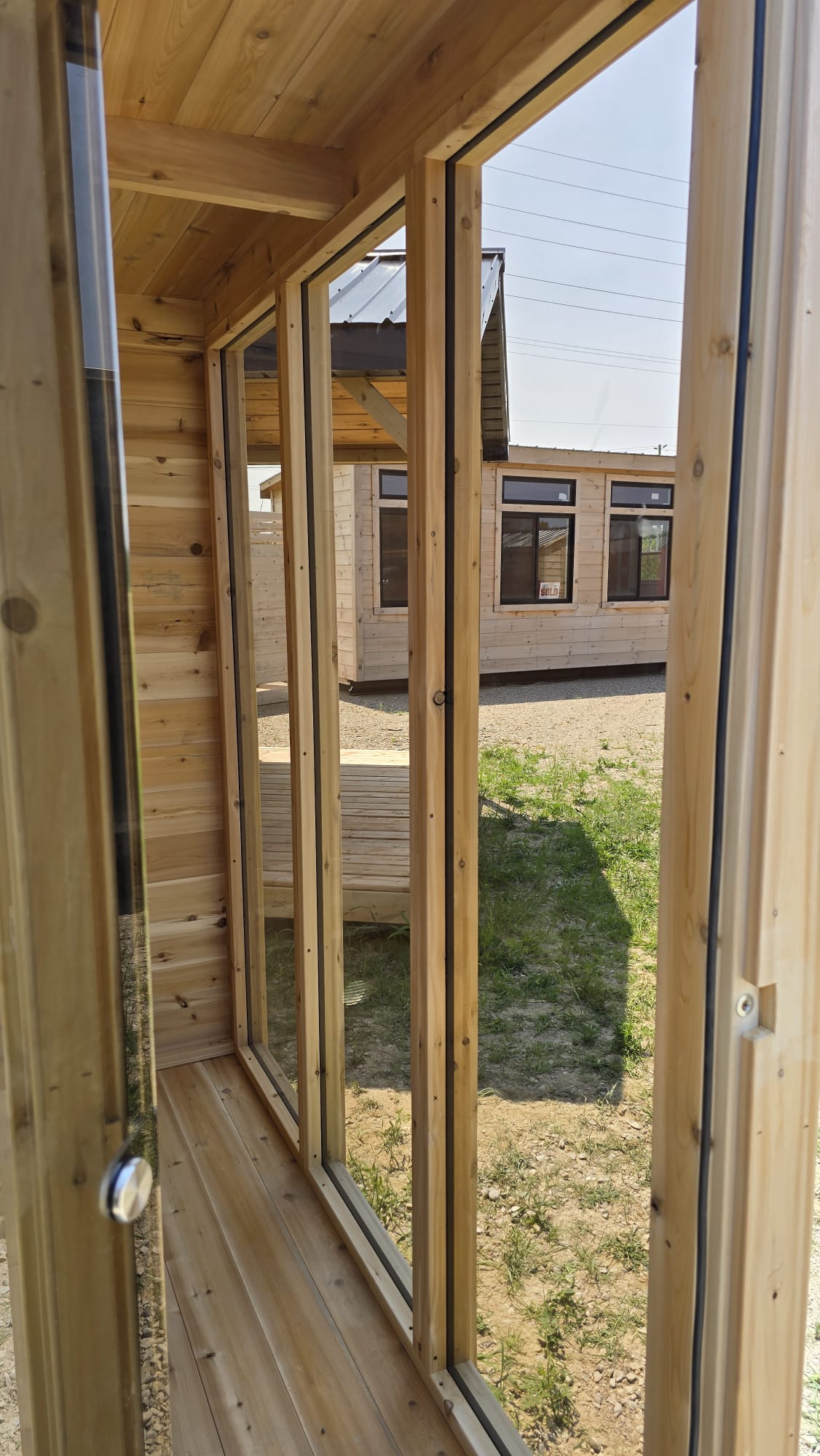 Wooden interior of a sauna with large windows showing an exterior view.