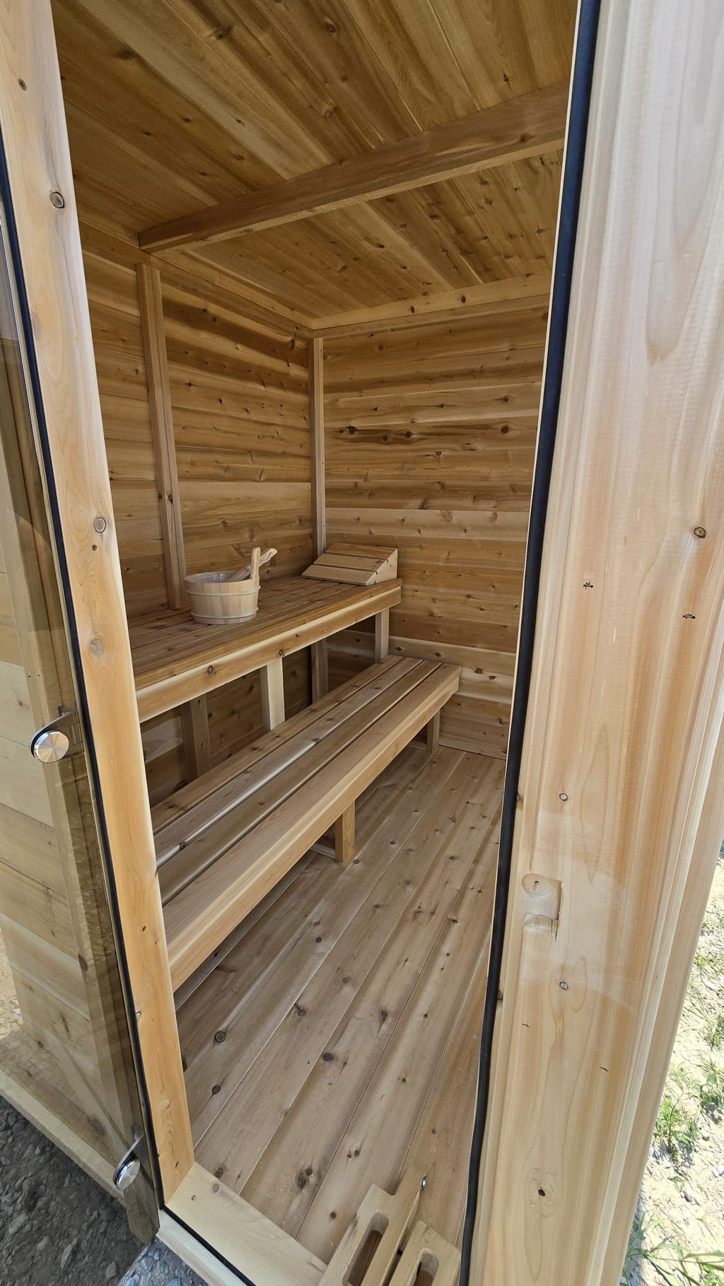 Wooden sauna with benches and a door open