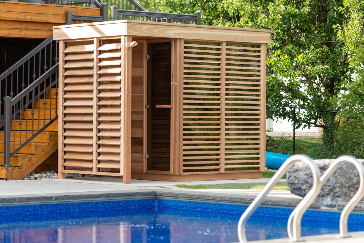 Wooden cedar sauna with shower and slatted doors next to a pool 
