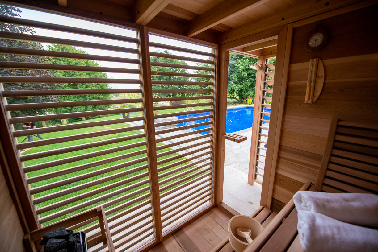 cedar sauna with glass doors open to a pool area