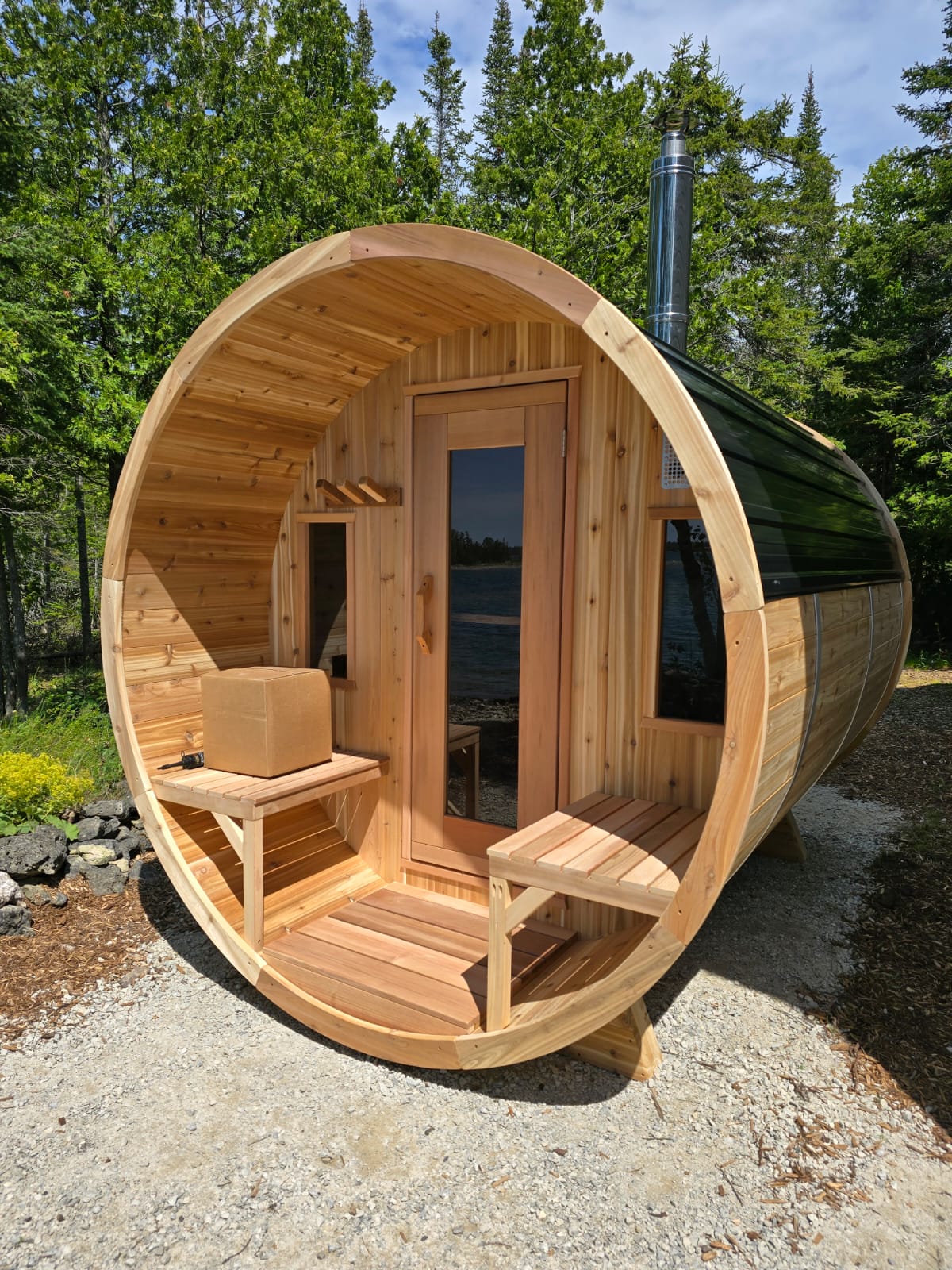 red cedar barrel sauna in woods with metal roof