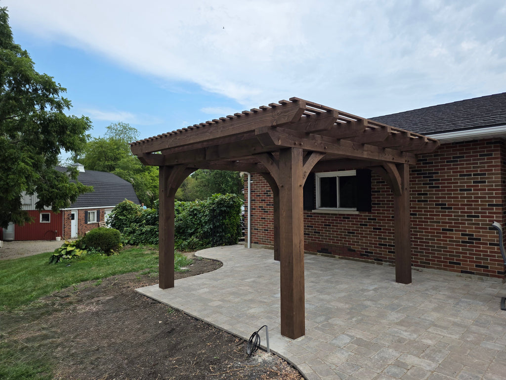 Wooden pergola attached to a brick house with a clear sky background