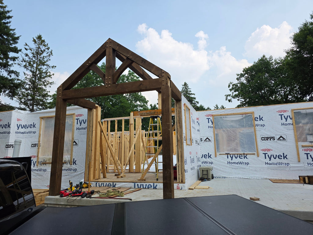 Wooden frame of a building under construction with Tyvek home wrap in the background.