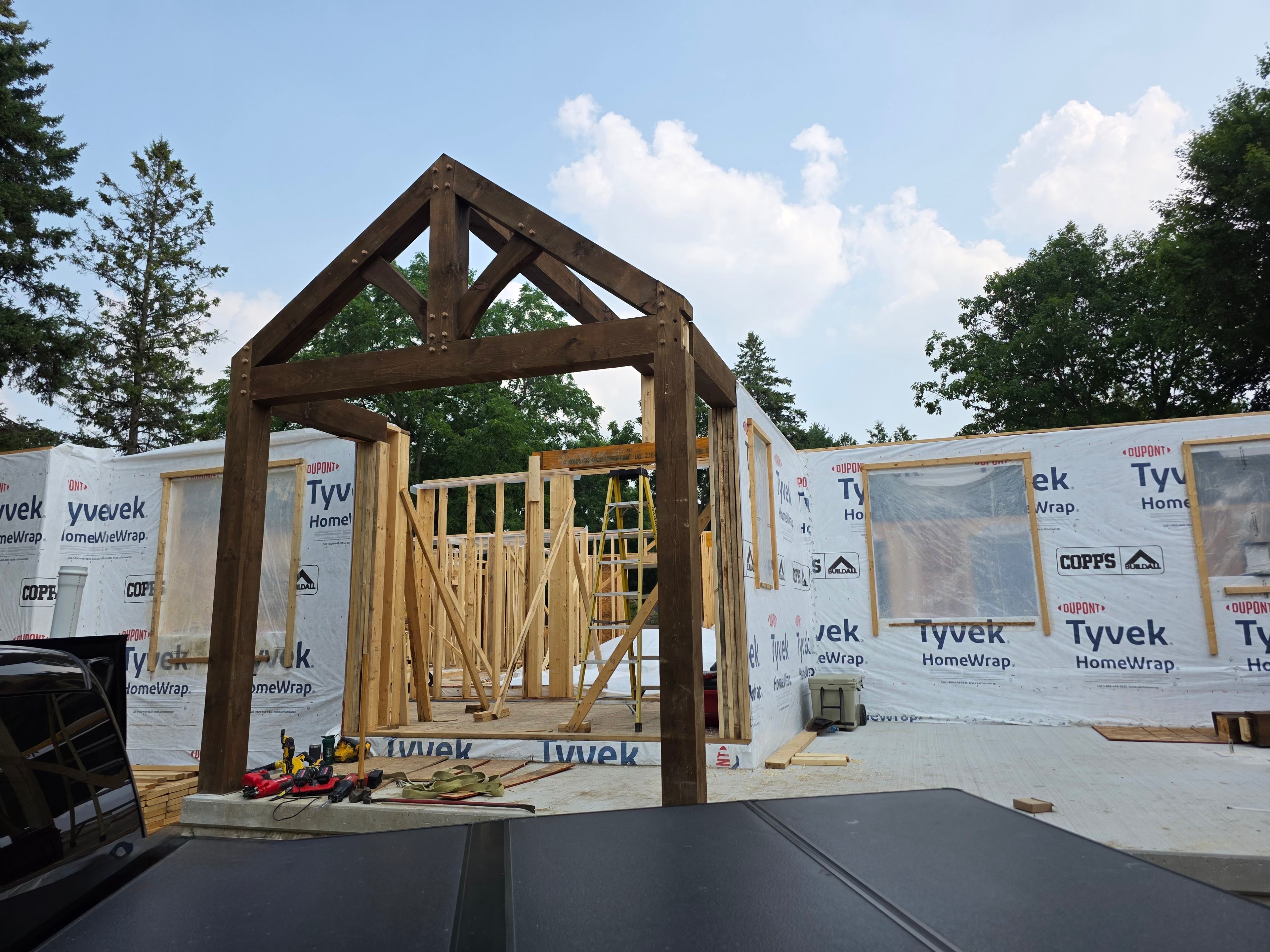 Wooden frame of a building under construction with Tyvek home wrap in the background.