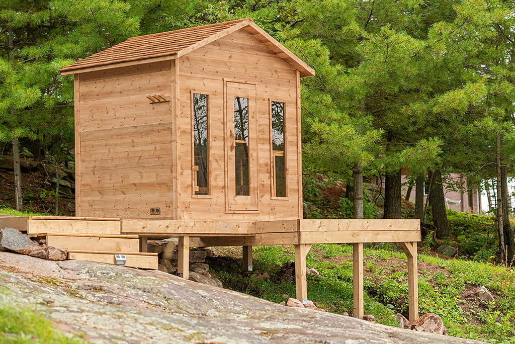 Wooden cabin structure on a rocky outcrop with trees in the background