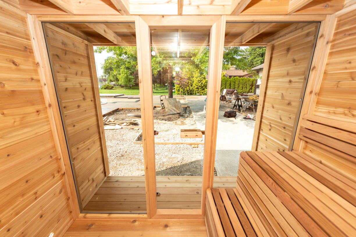 Wooden sauna with benches and large windows showing an outdoor view.