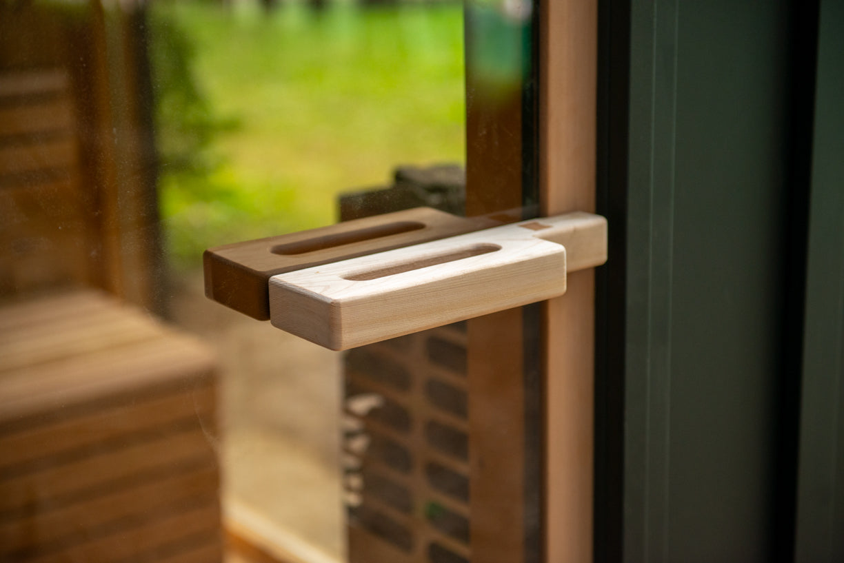 Close-up of a wooden door handle on a glass sauna door 