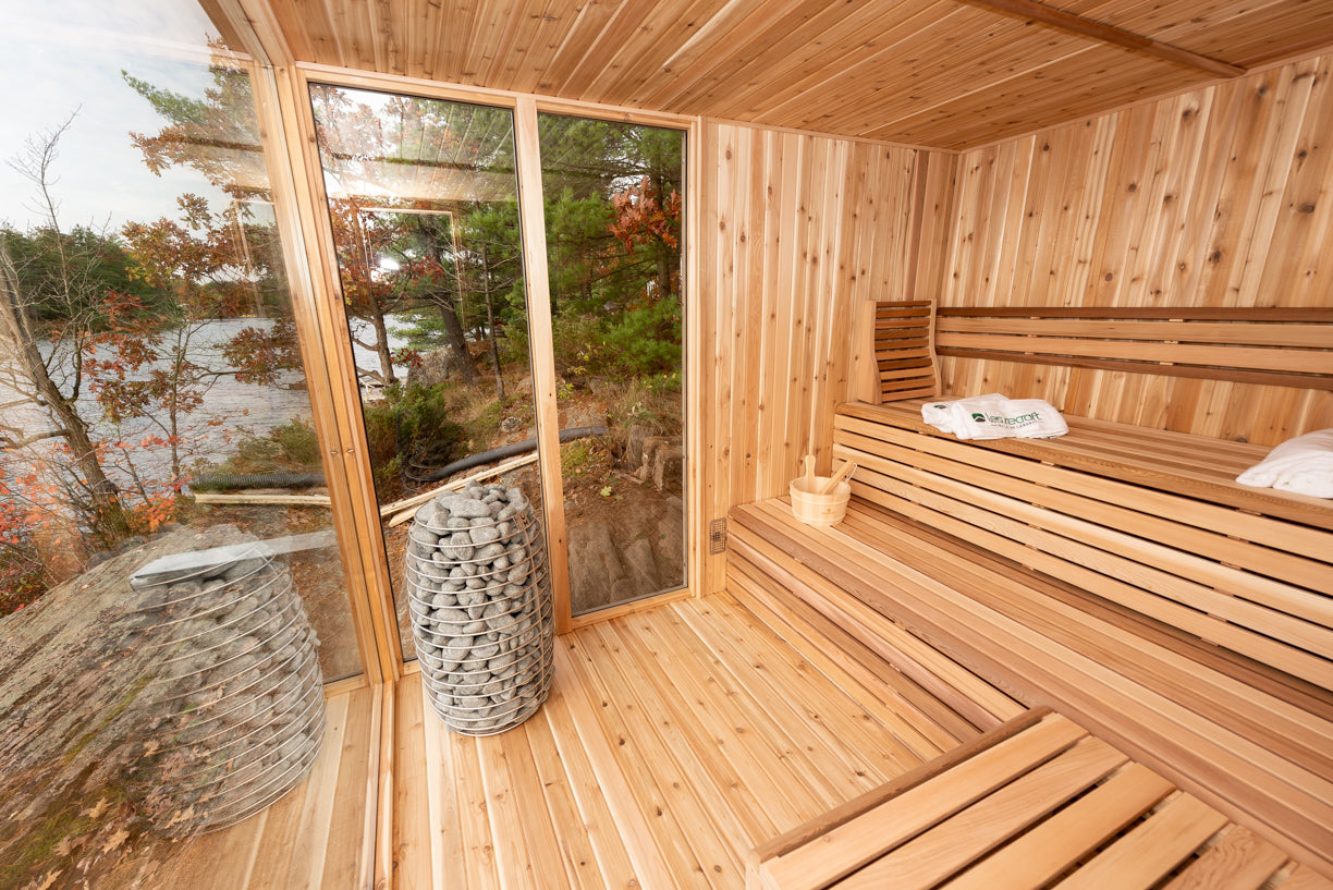Wooden sauna with a view of a lake and trees with stone standing electric heater