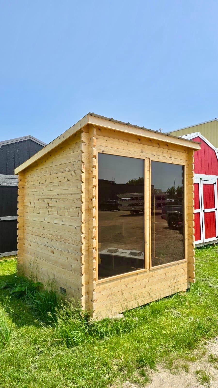 Wooden lean to sauna with large windows on a grassy area