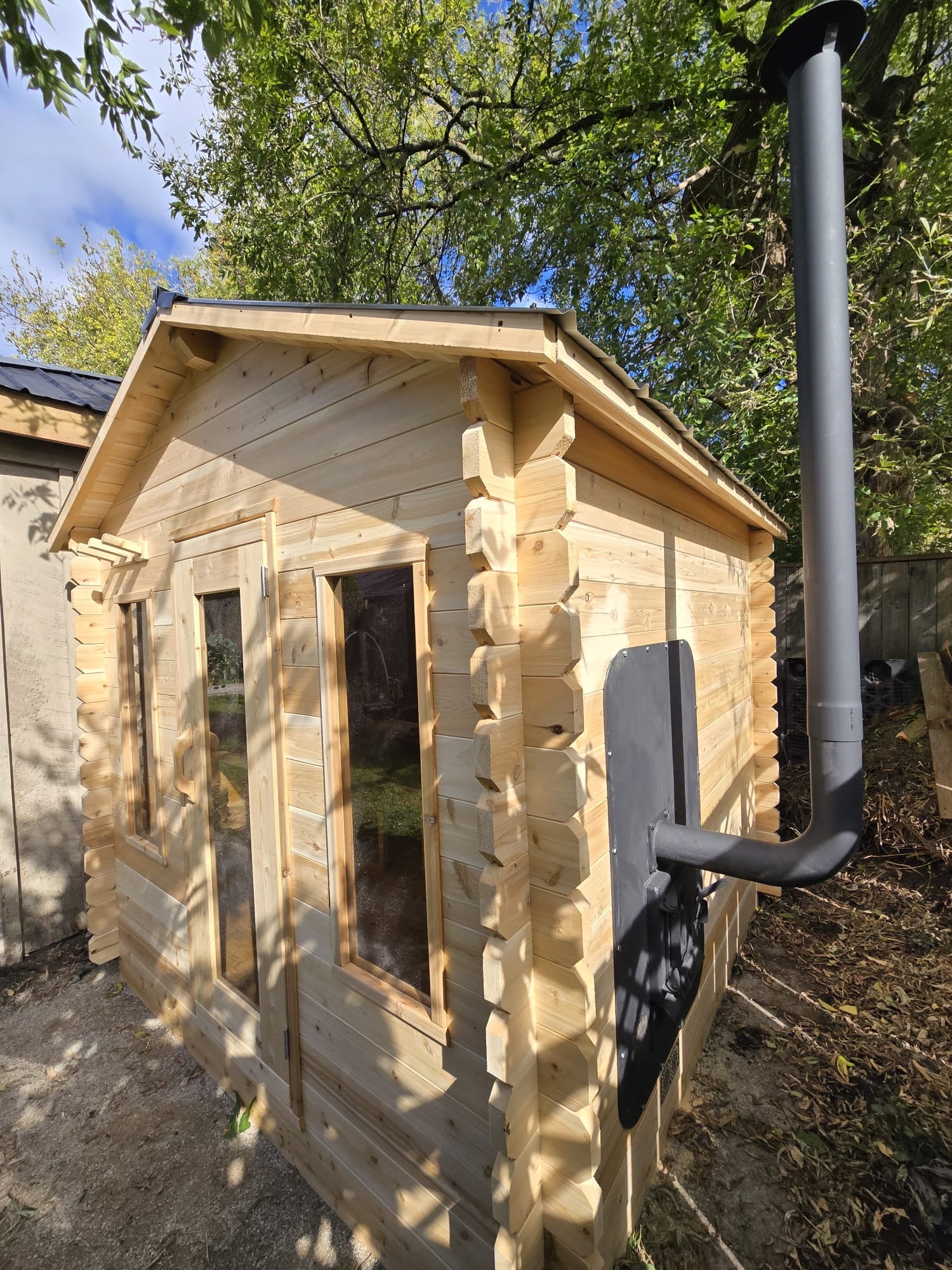 Wooden cabin sauna with an exterior fed wood heater in a natural setting