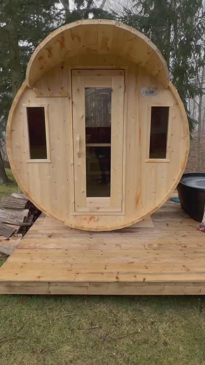 Wooden barrel sauna with a half moon window on a wooden deck